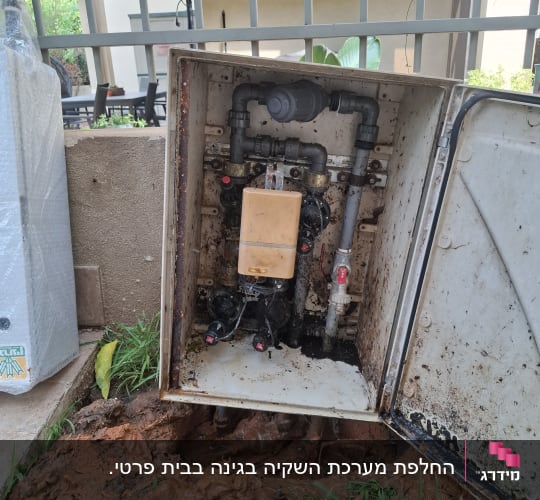 תיבת השקיה פתוחה עם צינורות ומערכת מים בגינה